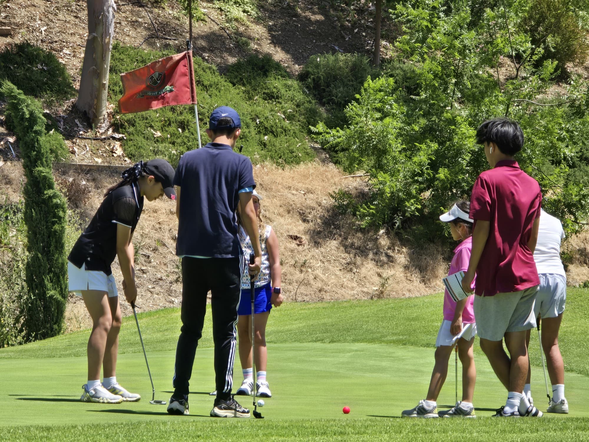 A Jucchou Golf coach giving a junior a putting lesson on the practice green